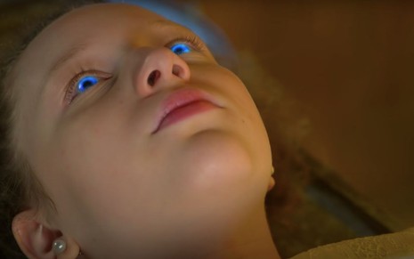 A atriz Manuela Kfouri abre os olhos com luzes azuis em cena como a personagem Ester na novela As Aventuras de Poliana, do SBT