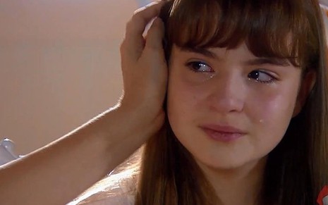 A atriz Sophia Valverde chora e recebe um afago em cena de As Aventuras de Poliana como a personagem Poliana