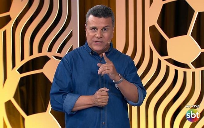 Téo José, narrador do SBT, com camisa azul em cenário de futebol