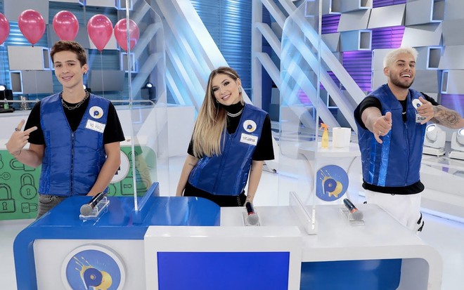 Separados por placas de acrílico em uma bancada azul estão João Guilherme, Virgínia Fonseca e Zé Felipe no Passa ou Repassa