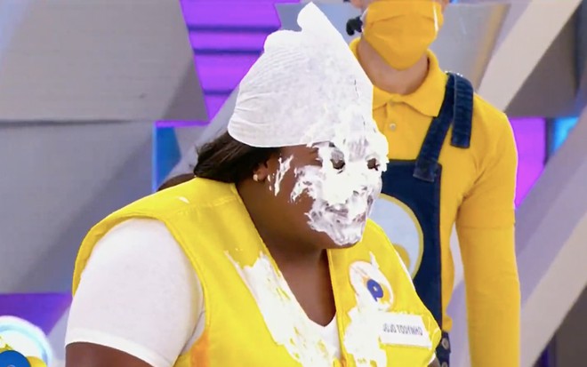 A cantora Jojo Todynho usa uma toalha branca no cabelo e tem o rosto coberto por chantilly no palco do Passa ou Repassa