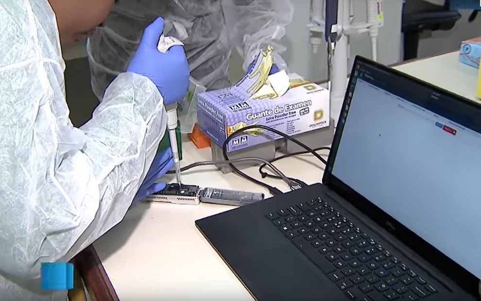 Reportagem do SBT em que uma cientista manuseando instrumentos de testes com o coronavírus