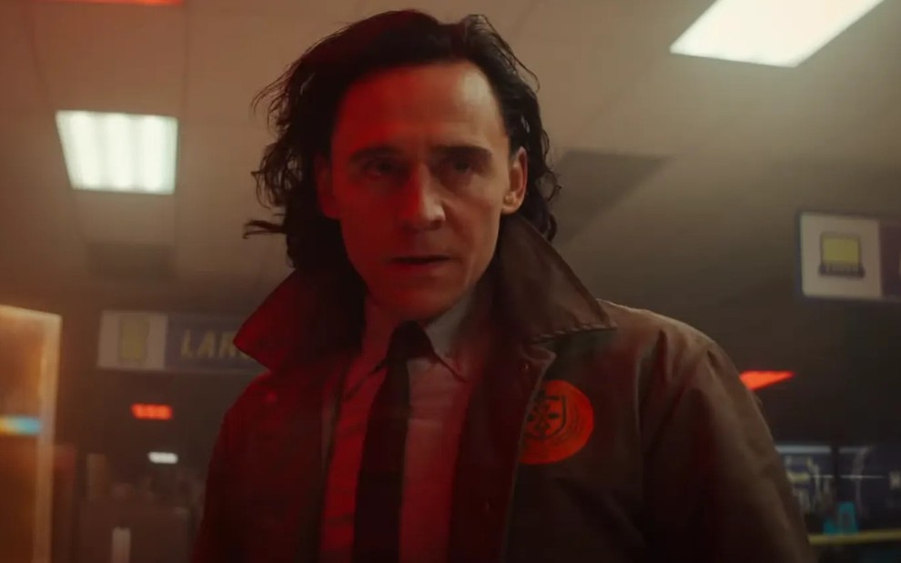 Loki (Tom Hiddleston) de terno e gravata, com olhar sério, em cena da série Loki