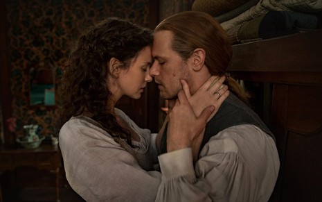 Claire (Caitriona Balfe) e Jamie (Sam Heughan) em Outlander abraçados e com as cabeças se tocando, com as mãos dela no pescoço dele