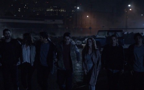 Grupo de personagens de Teen Wolf enfileirados lado a lado na parte de baixo com fundo de uma cidade escura