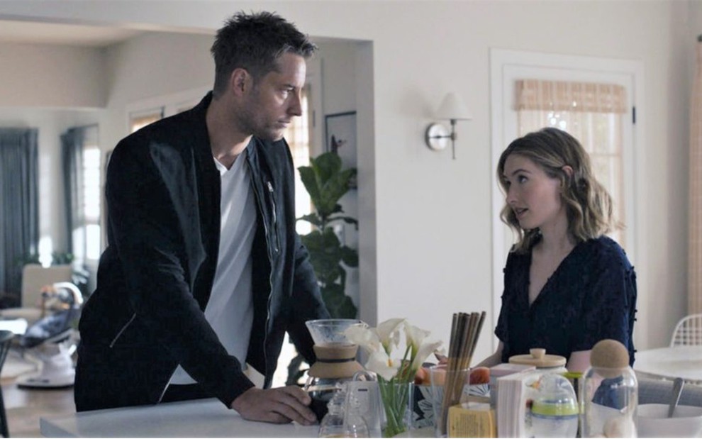 Kevin (Justin Hartley) em pé no lado esquerdo olha para Madison (Caitlin Thompson) sentada no lado direito em cenário de uma cozinha