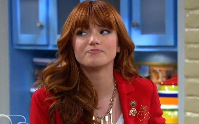 Com um cabelo ruivo jogado sobre o ombro direito, Bella Thorne segura o riso em imagem da série Shake It Up