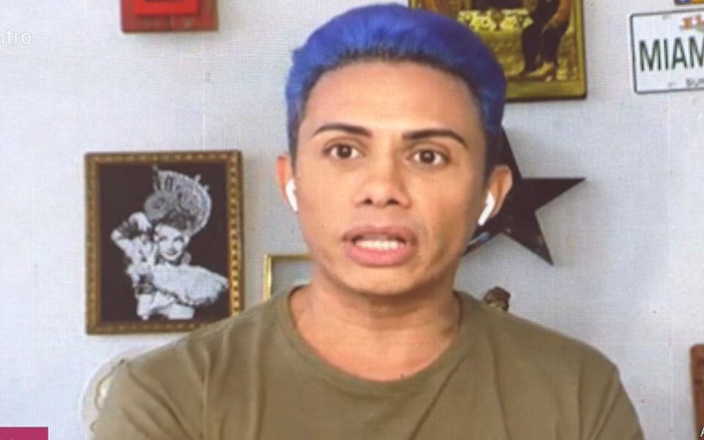 Silvero Pereira de cabelo azul e camiseta verde, em chamada de vídeo com Fátima Bernardes