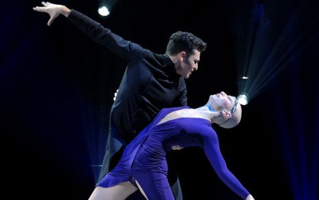 Vestindo preto, o dançarino Ezra Sosa segura a competidora Madison Jordan, de azul, durante dança em So You Think You Can Dance