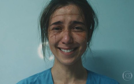 Marjorie Estiano em cena de Sob Pressão: com marcas de máscara hospitalares no rosto, a atriz sorri cansada para a câmera