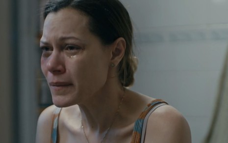 A atriz Hermila Guedes, com um olho roxo, chora em frente ao espelho em cena como a Sônia de Segunda Chamada