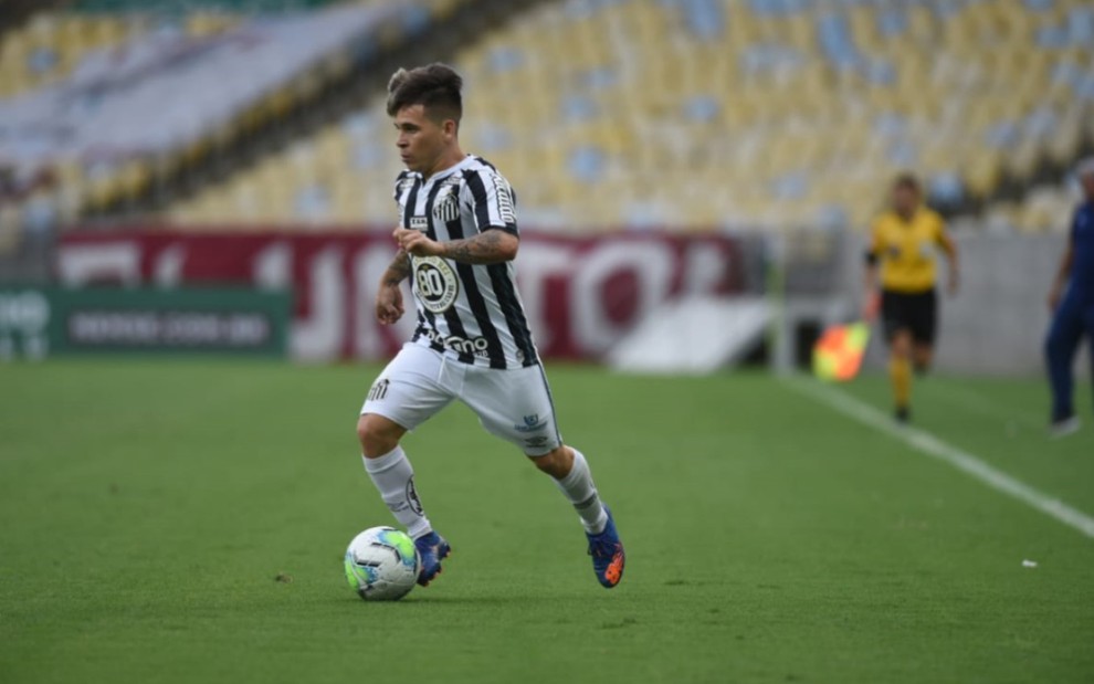 O jogador do Santos, Soteldo, em campo com a bola no pé, vestido com o uniforme do time nas cores branco e preto