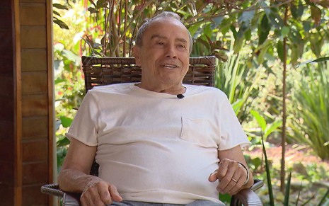 Stênio Garcia, sentado, de camiseta branca, em entrevista para o Domingo Espetacular, da Record