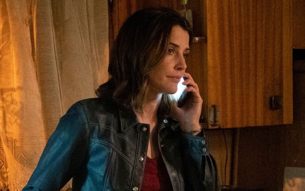 Em uma cozinha escura e suja, Cobie Smulders faz cara de triste ao usar um celular em cena de Stumptown