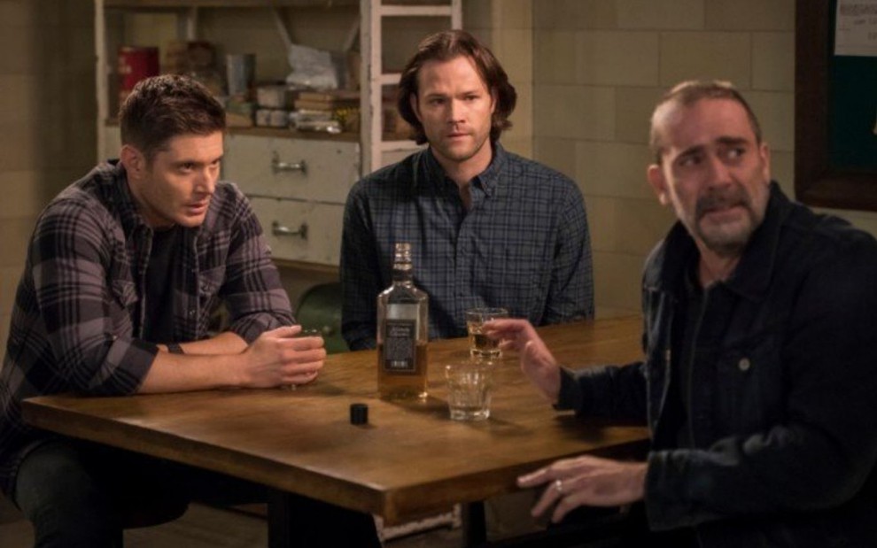Jensen Ackles, Jared Padalecki e Jeffrey Dean Morgan conversam sentados à mesa em episódio da 14ª temporada de Supernatural