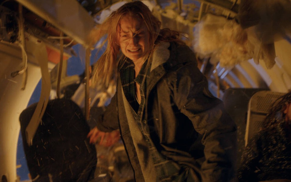 Dentro do que vem a ser um avião destroçado após a queda, a atriz Sophie Turner se desespera em cena da série Survive