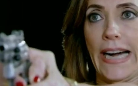 A atriz Christiane Torloni caracterizada como Tereza Cristina segura um revólver em cena da novela Fina Estampa, da TV Globo