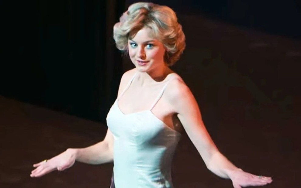 A atriz Emma Corrin em cena com vestido branco, como princesa Diana, dançando em The Crown