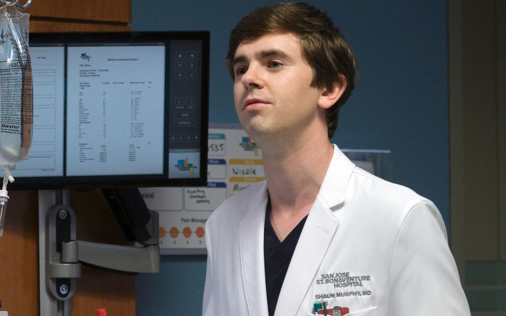 Em uma quarto hospitalar, Freddie Highmore aparece com um jaleco branco de médico em cena de The Good Doctor