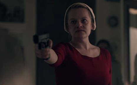 Elisabeth Moss aponta uma pistola em cena da série The Handmaid's Tale