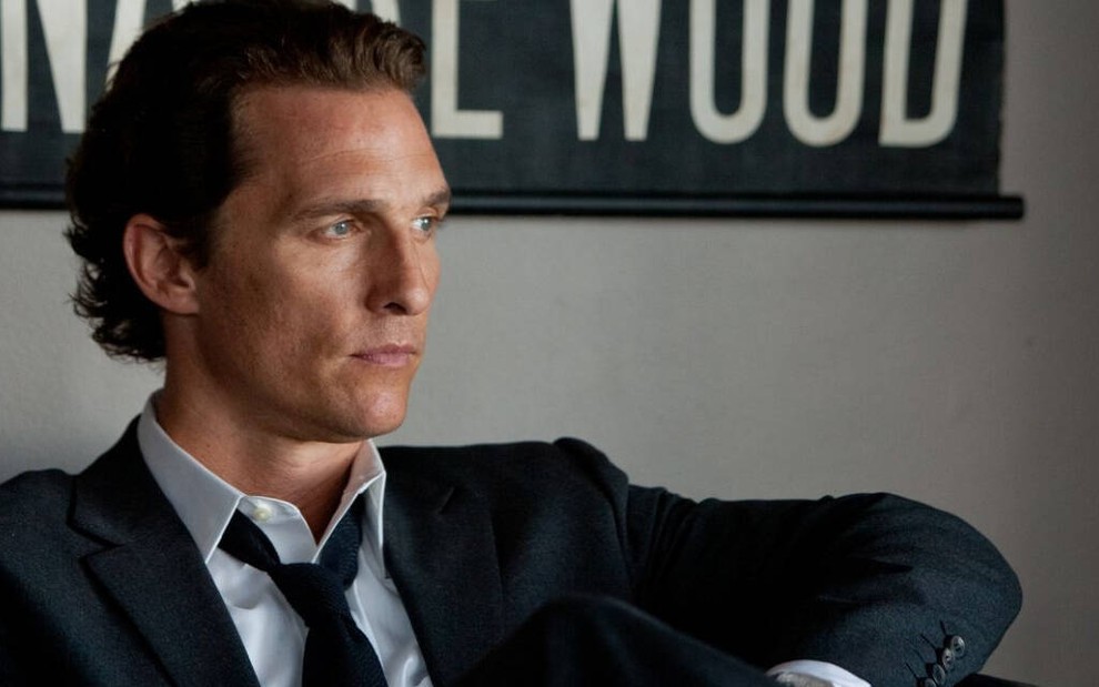 Sentado de terno, Matthew McConaughey olha para o nada em cena do filme The Lincoln Lawyer