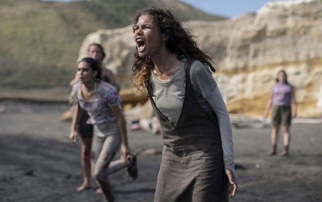 Helena Howard grita na praia ao lado de outras meninas em cena da série The Wilds