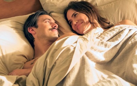 Deitados em uma cama e com os corpos sobertos, Milo Ventimiglia e Mandy Moore trocam olhares em cena de This Is Us