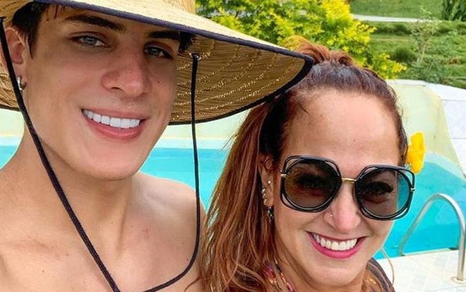 Tiago Ramos sem camisa, se chapéu de palha; Nadine Gonçalves de óculos escuros