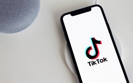 Um celular apoiado em uma mesa com a tela branca e o símbolo do TikTok
