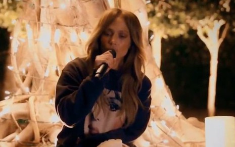 A cantora Jennifer Lopez canta em uma árvore iluminada com luzes de Natal