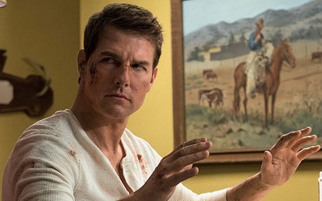 Tom Cruise com machucados no rosto e as mãos em sinal de rendição em cena do filme Jack Reacher - Sem Retorno