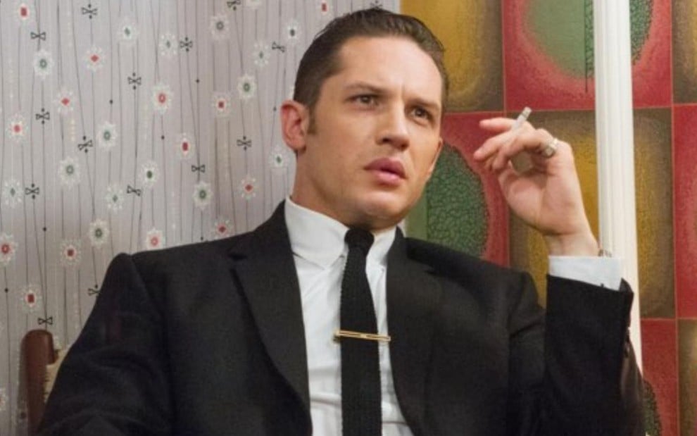 Tom Hardy segura um cigarro na mão e faz expressão de incredulidade em cena do filme Lendas do Crime (2015)