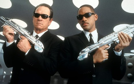 Tommy Lee Jones e Will Smith usam ternos e óculos escuros e seguram armas em MIB - Homens de Preto 2 (2002)