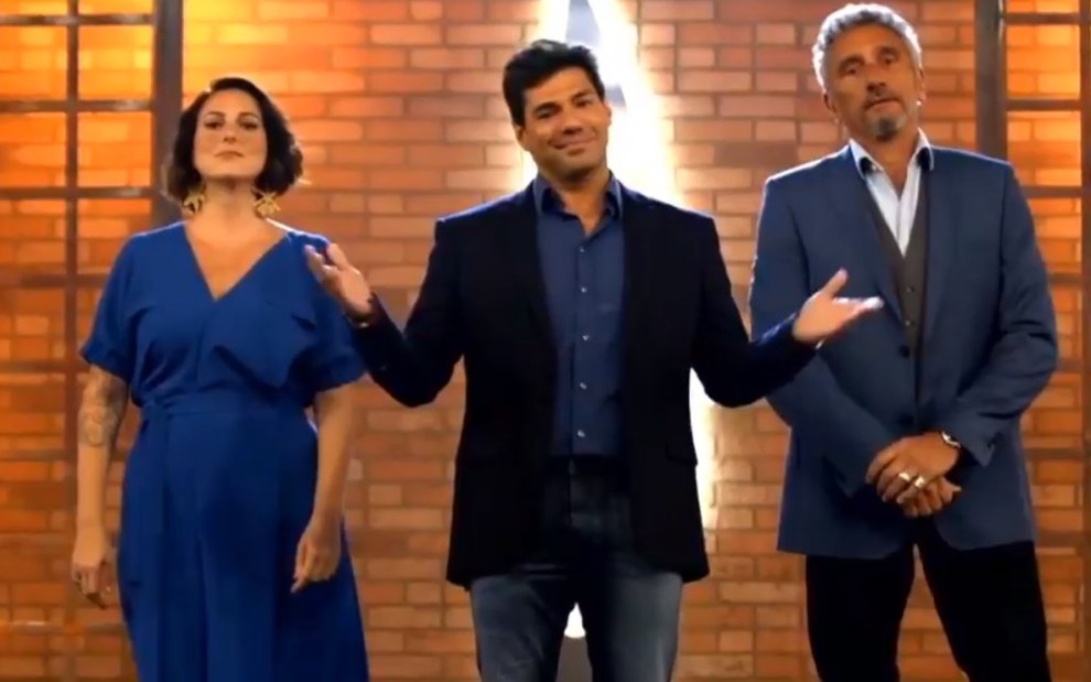 Ailin Aleixo, Felipe Bronze e Emmanuel Bassoleil lado a lado dentro de um cenário de reality show