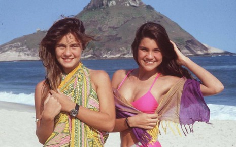 As atrizes Adriana Esteves e Flávia Alessandra sorriem na praia em gravação de Top Model (1989)