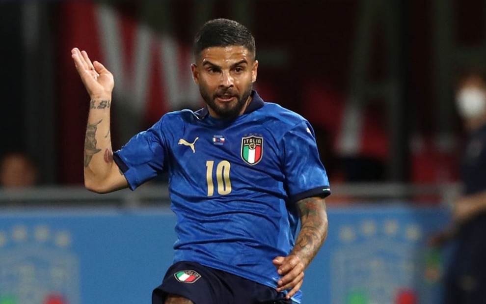 O atacante Insigne chuta a bola em jogo da Itália; ele está de uniforme azul