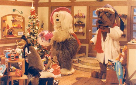 Bonecos que representam os personagens Priscila e JF montam uma árvore de Natal no estúdio do programa