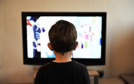 Criança de costas olhando para a tela da TV