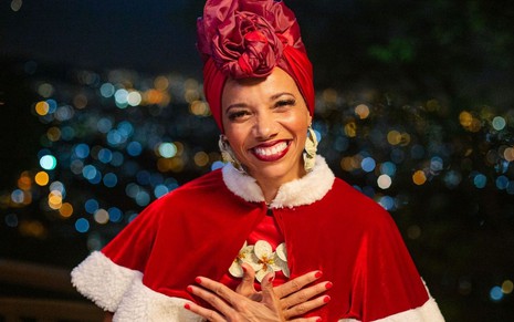 A atriz Verônica Bonfim sorri para a câmera vestida de Mamãe Noel na série Liga de Natal - Uma Aventura no Rio