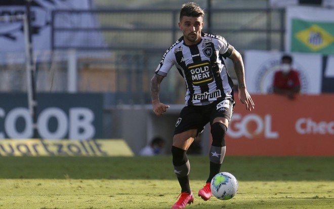 O jogador do Botafogo Victor Luis em lance com bola a frente ao corpo, com uniforme do time nas cores preto e branco