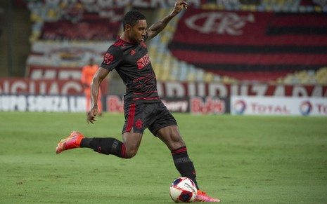 O jogador do Flamengo, Vitinho, em lance no campo vestido com o uniforme do time nas cores preto e vermelho