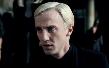 O ator Tom Felton com expressão séria como o personagem Draco Malfoy no fihlme Harry Potter e as Relíquias da Morte: Parte 1