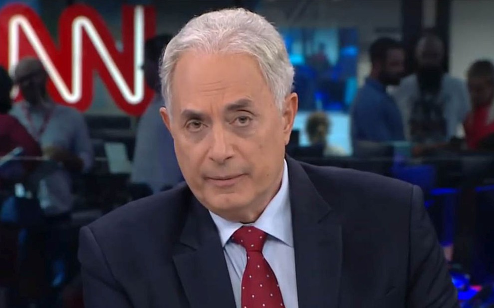 William Waack na bancada da CNN Brasil, de camisa, terno e gravata vermelha