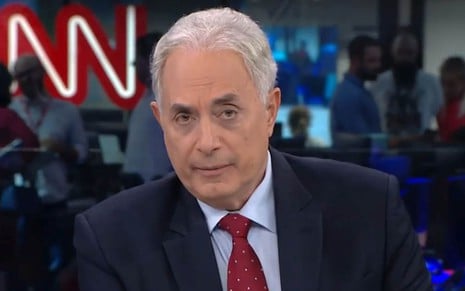 William Waack na bancada da CNN Brasil, de camisa, terno e gravata vermelha