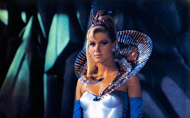 Xuxa com um vestido azul e acessórios envolvendo seu pescoço e seu cabelo