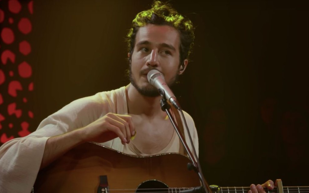 Sentado, Tiago toca violão e canta em seu Acústico MTV