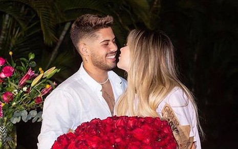 Zé Felipe e Virgínia aparecem abraçados, sorrindo um para o outro, e segurando, juntos, um buquê de rosas vermelhas