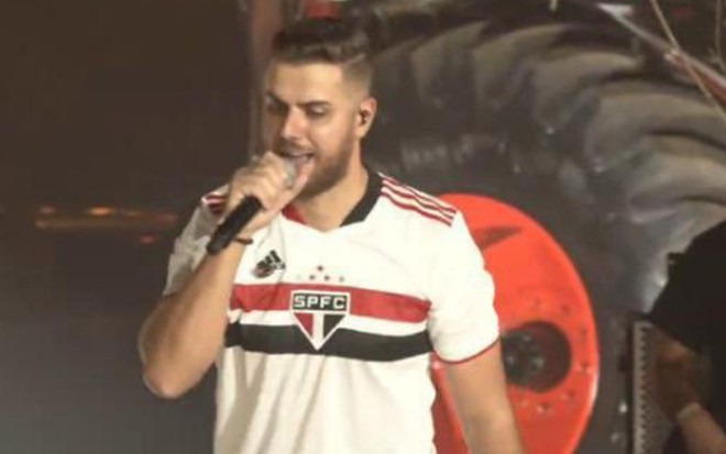 Zé Neto cantando em live e usando a camisa do time São Paulo