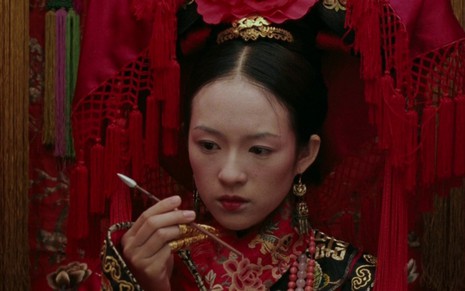 Ziyi Zhang, como Jiao Long, observa uma lança em cena de O Tigre e o Dragão (2000)