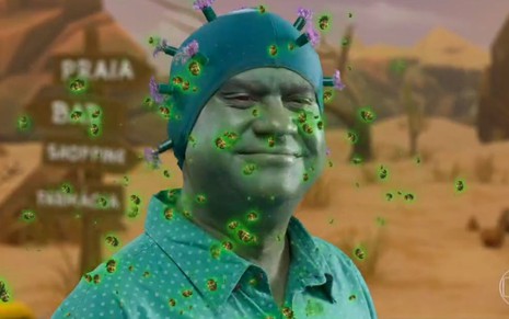 Com uma fantasia verde de coronavírus, o ator Welder Rodrigues sorri em cena exibida pelo Zorra